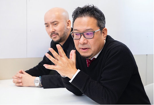 学習用ロボット「あるくメカトロウィーゴ」を開発した、リビングロボットの川内康裕さん（手前）、その開発をともに支えたクリエーターの亀井栄輔さん（奥）
